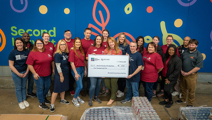 A group of volunteers from Elan Credit Card and Envision Credit Union hold a large promotional check. 